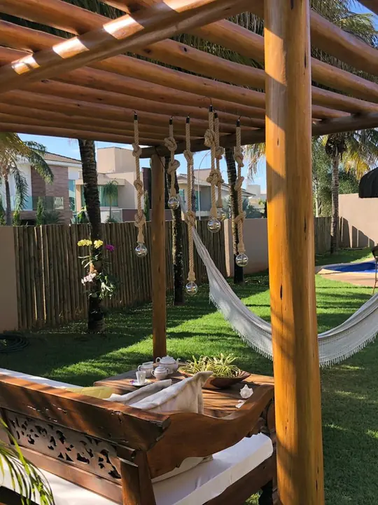 Pergolado de madeira com rede e mobiliário em jardim